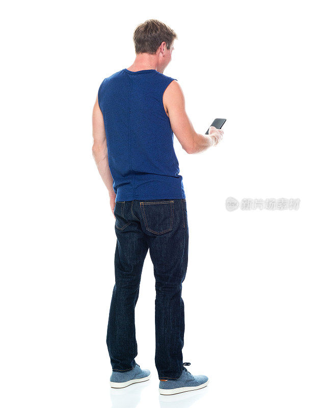 全长/后视镜/后视镜/一人独/一人20-29岁的成年帅哥白人男性/青年男子无袖站立穿着背心/牛仔裤/长裤/帆布鞋/酷的态度和拿着手机